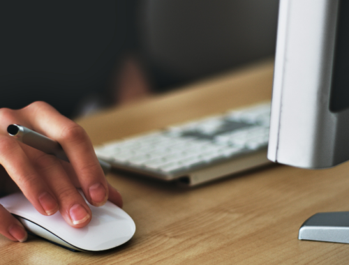 Mulher no computador com uma caneta na mão procurando emprego